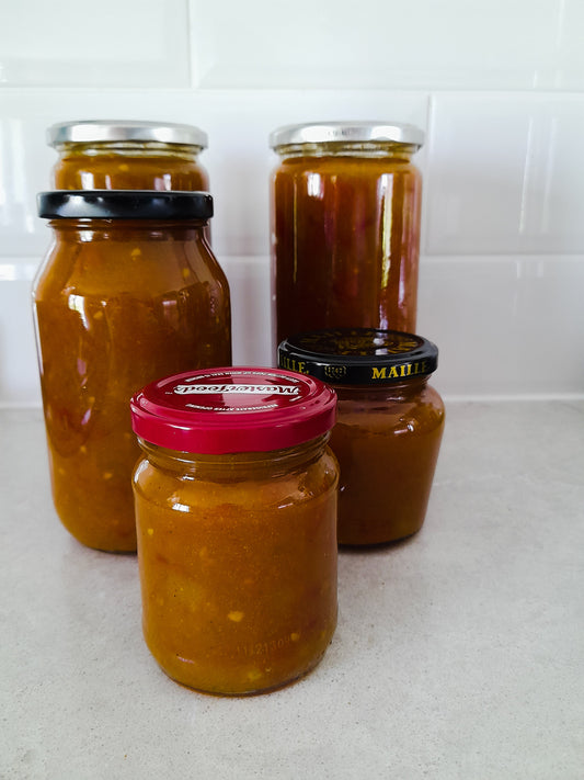 2 large, 1 medium & 2 small jars of Rustic Aussie Tomato Relish sitting on a bench. 
