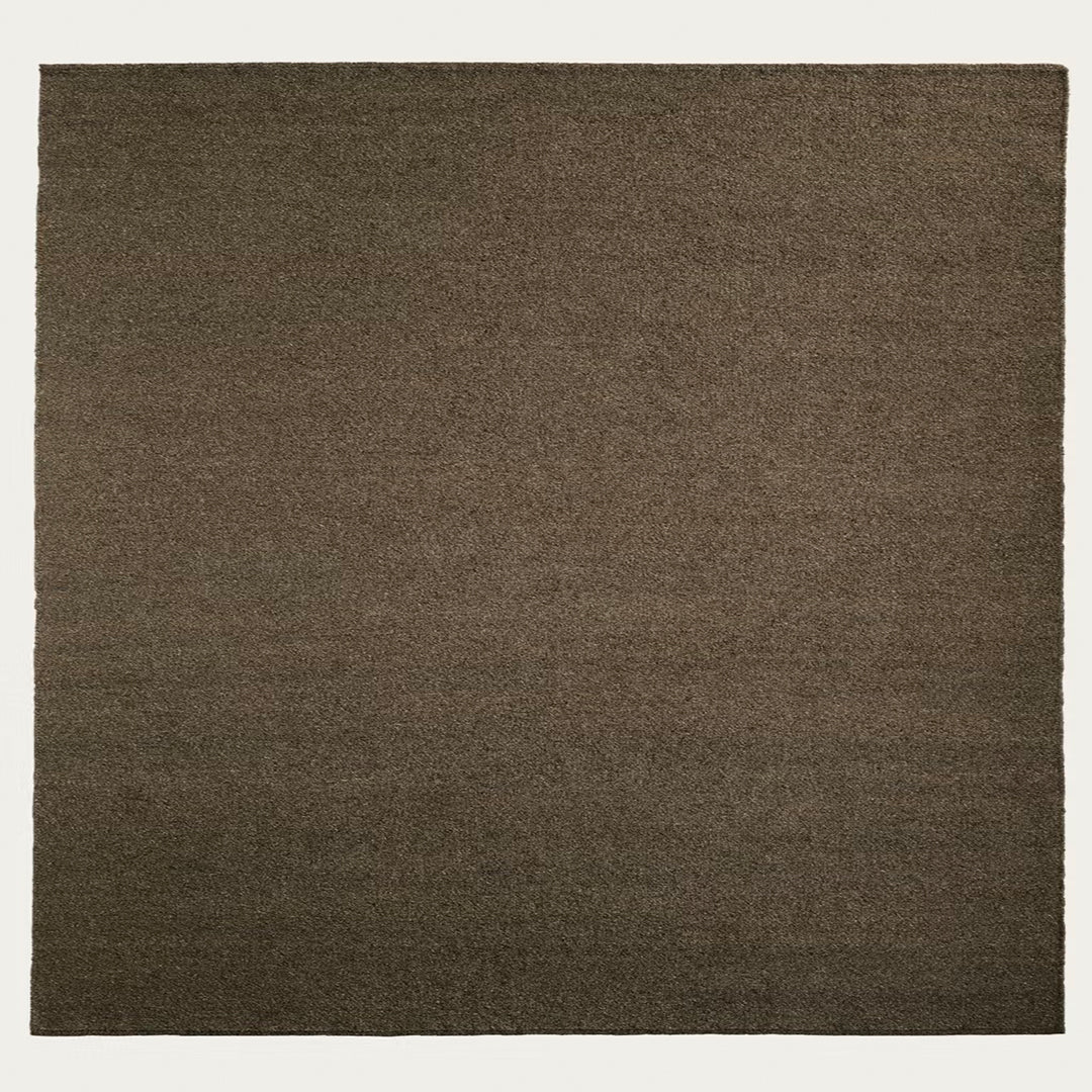 Brown square rug with a textured pattern on a white background