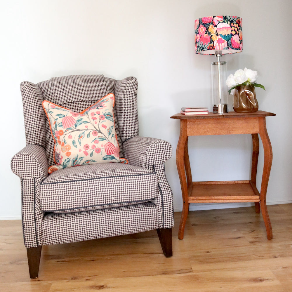 After Photo of a Navy Houndstooth and contrast piping wingback that Toowoomba Upholsterer Luxe & Humble reupholstered. Styled with a custom made floral pillow, restored silky oak table and bespoke floral lampshade. 