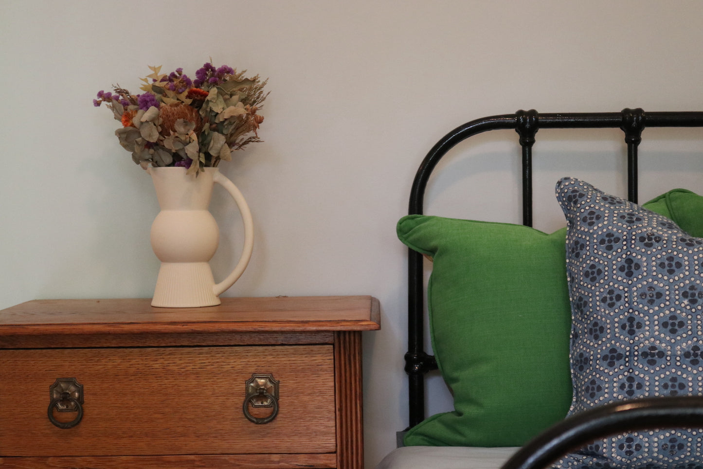 Ash Block Printing - Mewari - Denim 55cm Scatter Cushion in situ on a wrought iron bed.