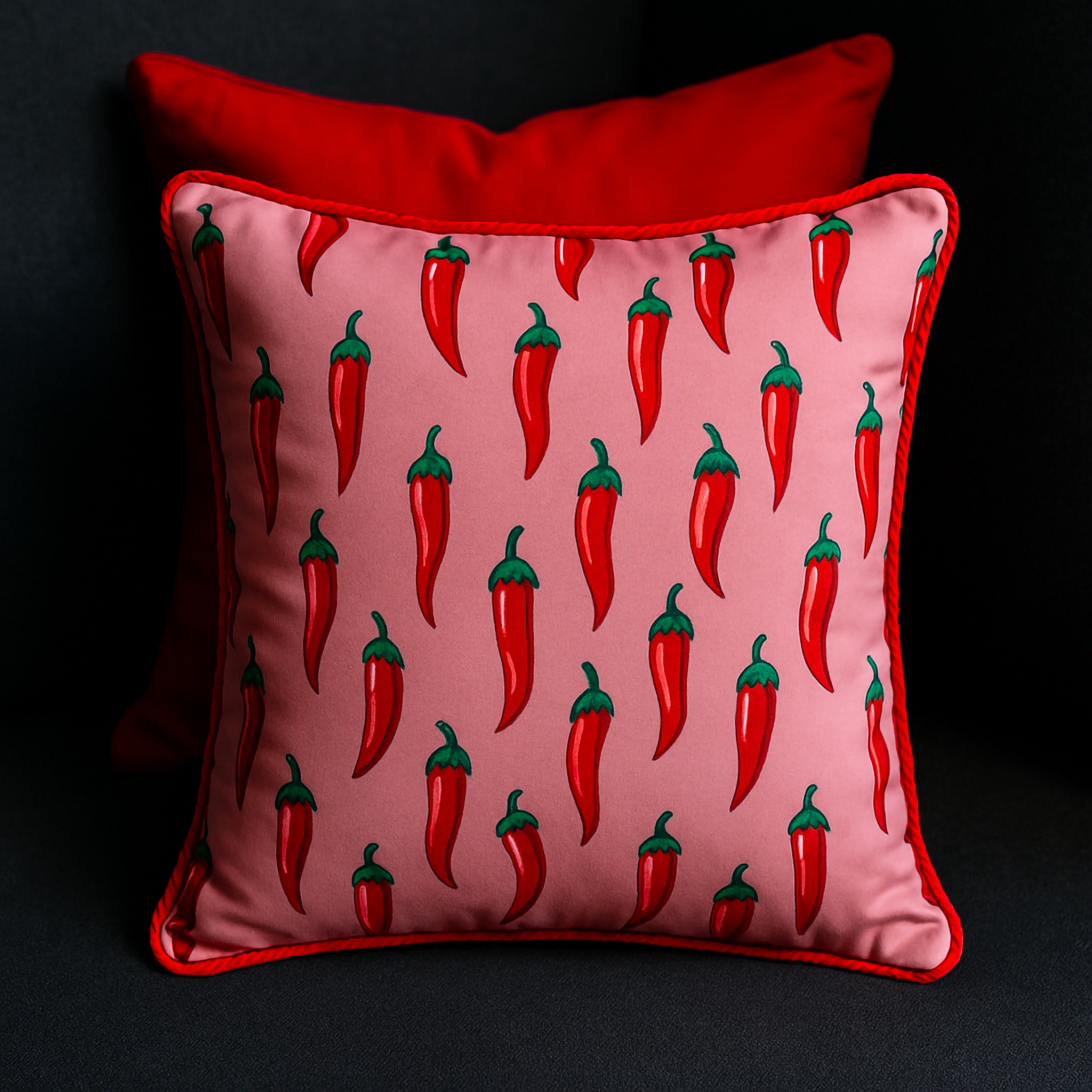 Bespoke 50 x 50 cm cushion with bold chili pepper print on pink fabric

Square cushion featuring red chili pepper pattern with red piping trim

Playful chili pepper cushion styled on dark sofa with vibrant red accents