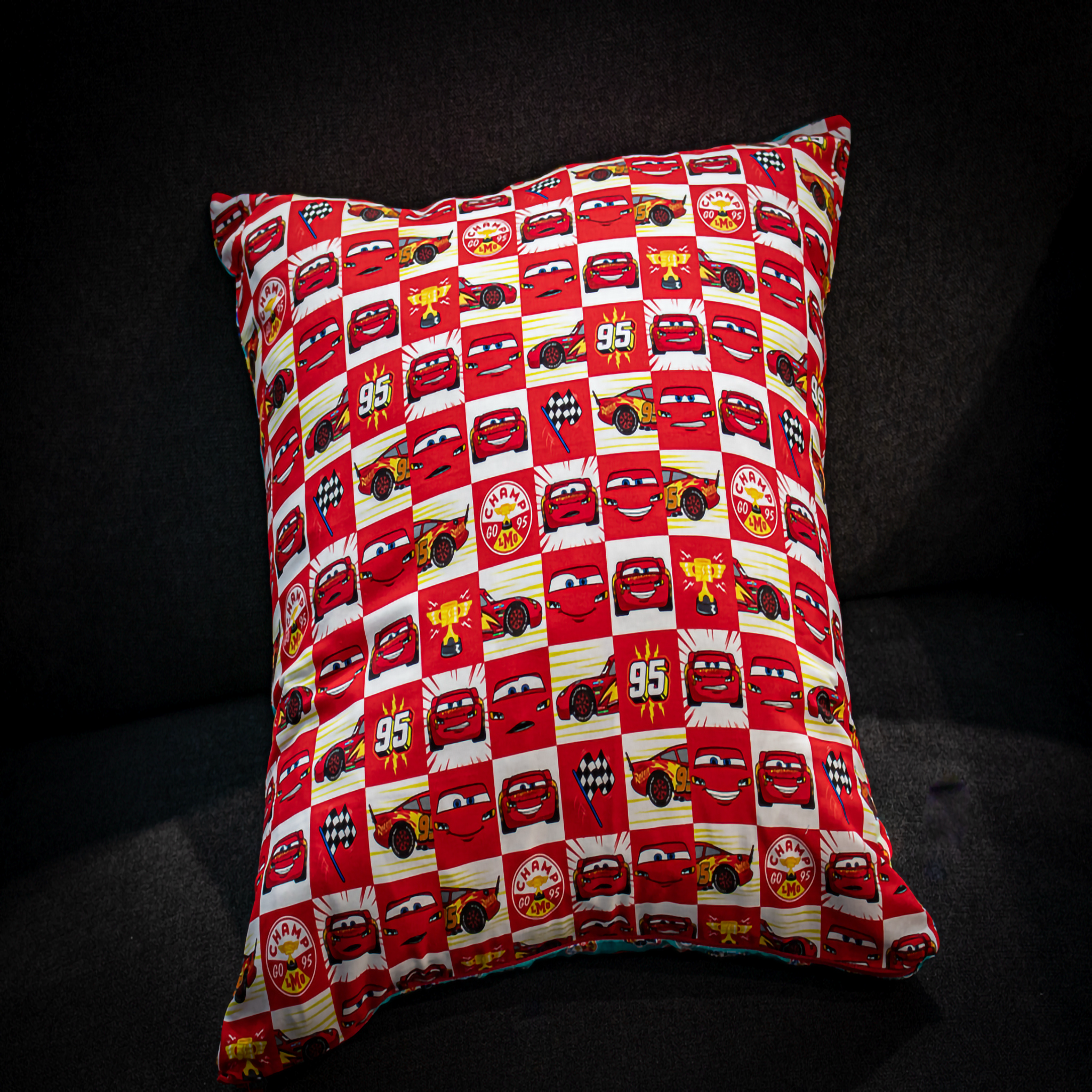 Disney cars cushion with red and white checkered pattern. Reversible teal side. 
