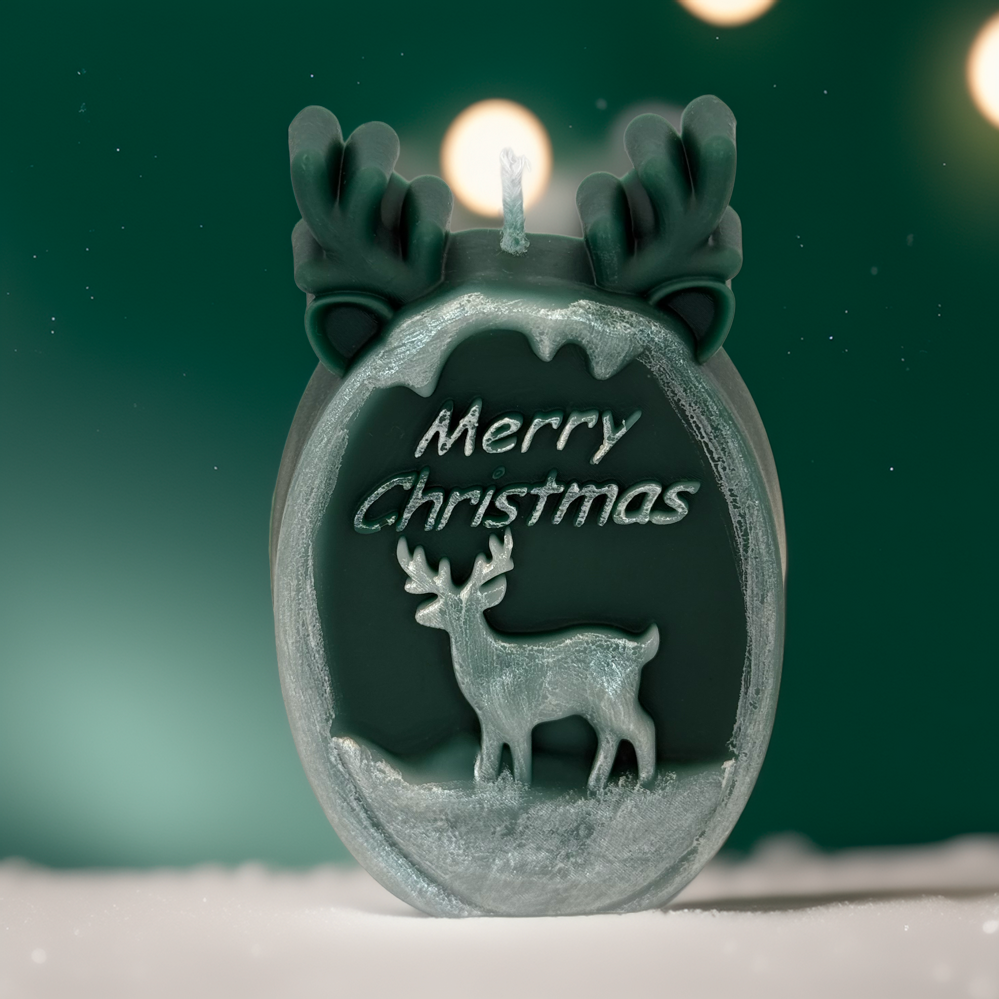 Decorative green Christmas candle featuring reindeer embossing and antler design, styled with a festive glowing background. Ideal for Australian Christmas décor, gift boxes, home styling and seasonal displays from Luxe & Humble.