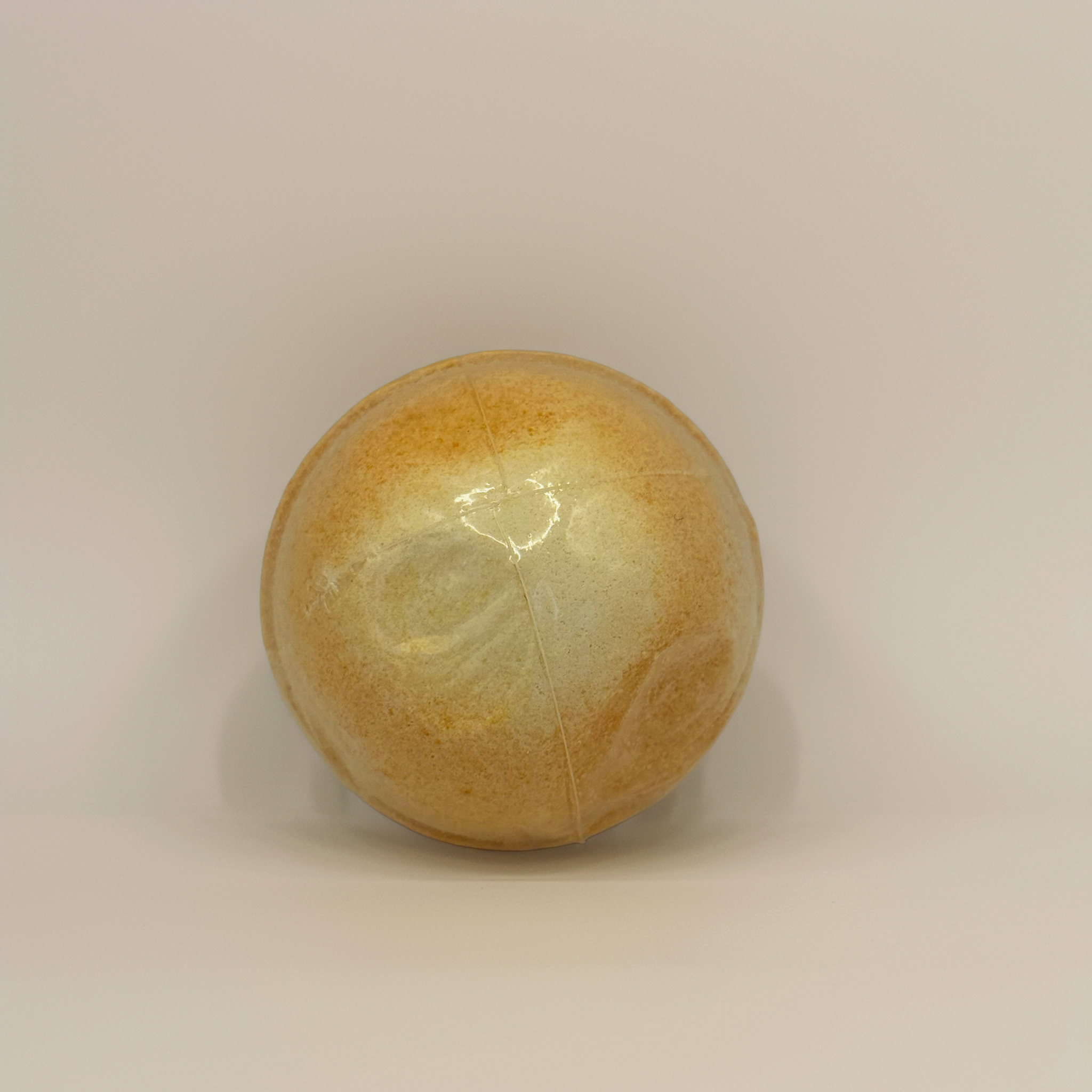 A shimmering gold bath bomb displayed against a glowing golden bokeh background. A luxurious Australian-made bath bomb by Luxe & Humble, ideal for gifting, spa bundles and summer self-care rituals