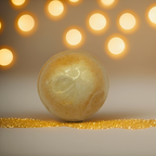 A shimmering gold bath bomb displayed against a warm festive backdrop with golden lights. A luxurious, Australian-made bath bomb by Luxe & Humble, ideal for Christmas gifting, spa bundles and self-care lovers.