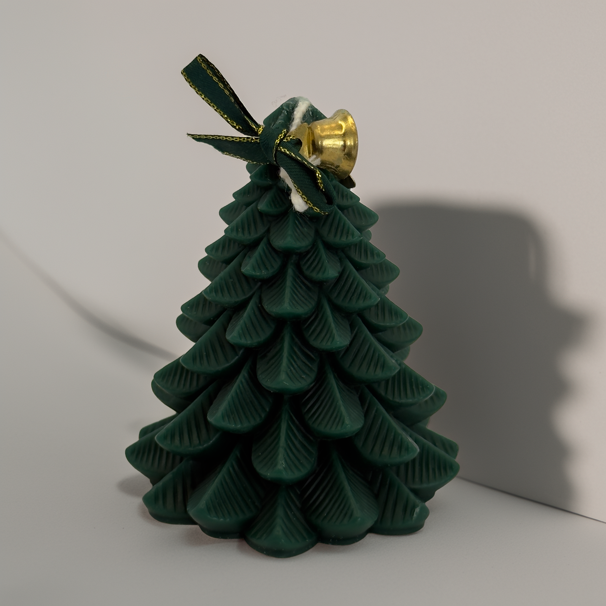 A sculpted green Christmas tree candle with detailed layered branches, topped with a gold bell and green ribbon. Photographed on a clean white background for Shopify product listings. Premium festive candle available Australia-wide from Luxe & Humble.