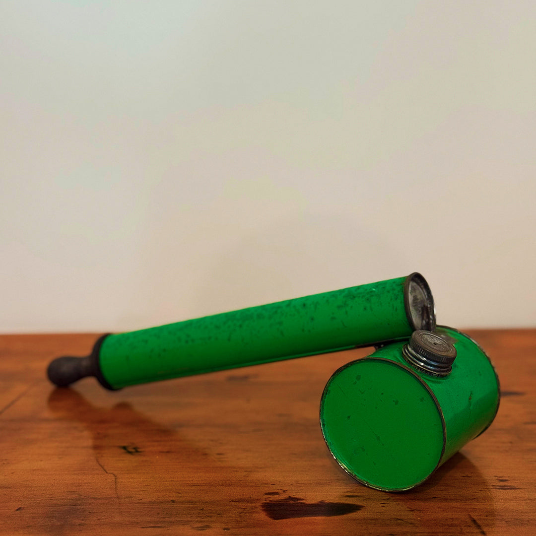 Vintage green insect spray hand pump with a shiny metal cap, displayed on a wooden surface, showcasing its smooth green finish and retro design.