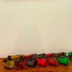 Collection of vintage metal cans with different colors on a wooden surface against a white wall.