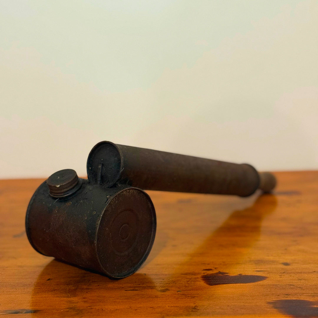 Vintage brown insect spray hand pump with a worn exterior and metal cap, displayed on a wooden surface showcasing its retro, rustic design.