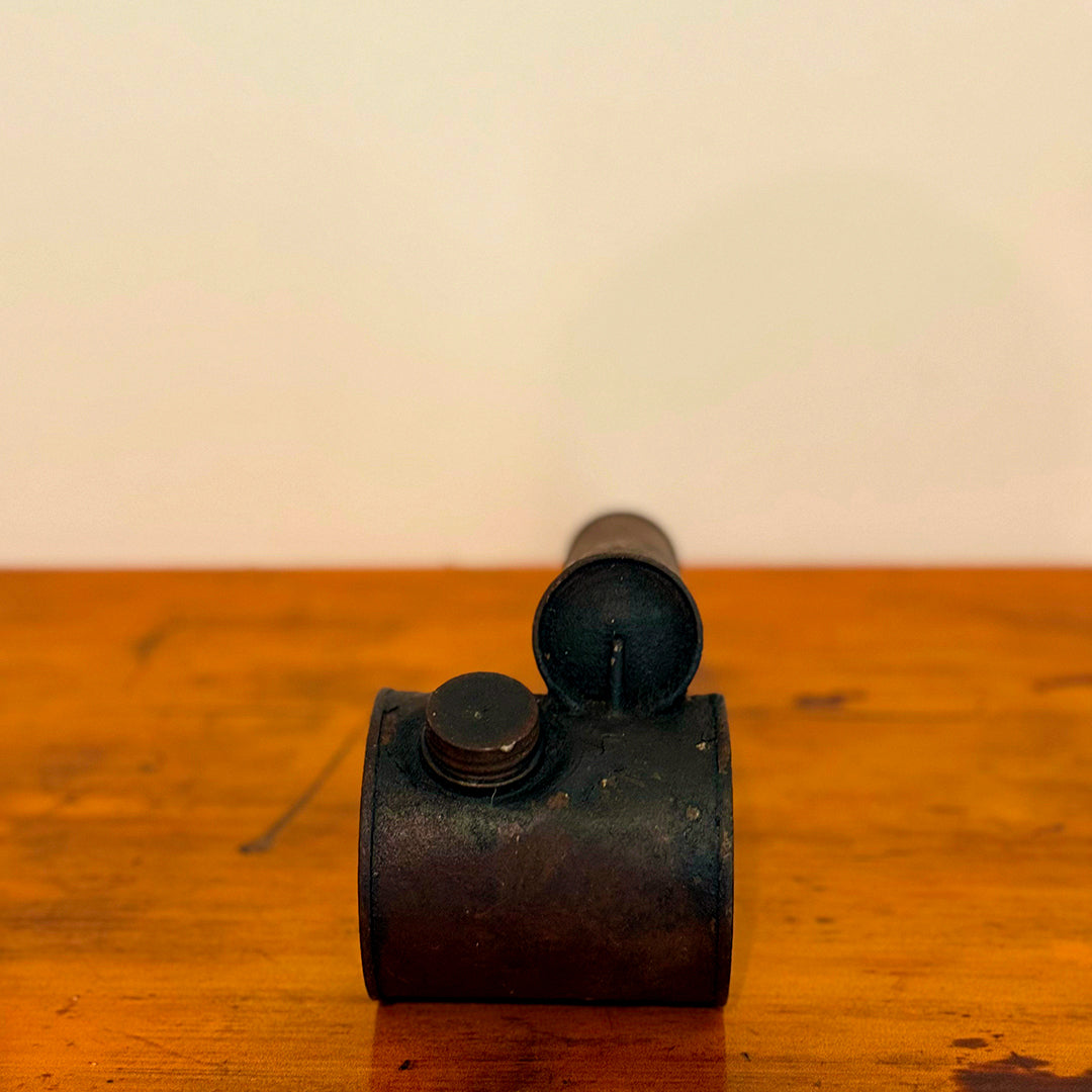 Vintage brown insect spray hand pump with a worn exterior and metal cap, displayed on a wooden surface showcasing its retro, rustic design.
