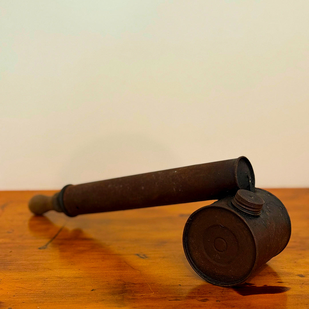 Vintage brown insect spray hand pump with a worn exterior and metal cap, displayed on a wooden surface showcasing its retro, rustic design.