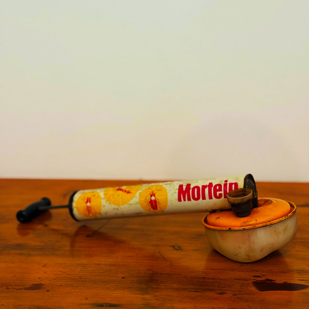 Vintage Mortein insect spray hand pump with an orange base, featuring the classic Mortein logo and vintage design, displayed on a wooden surface.