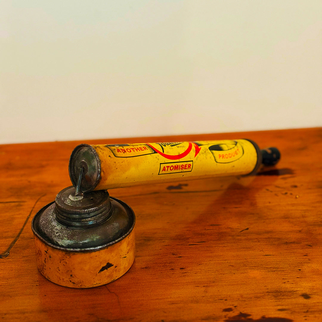 Vintage Insect Spray Hand Pump with red and worn surface, displaying classic mid-20th-century design, shown on a wooden surface.
