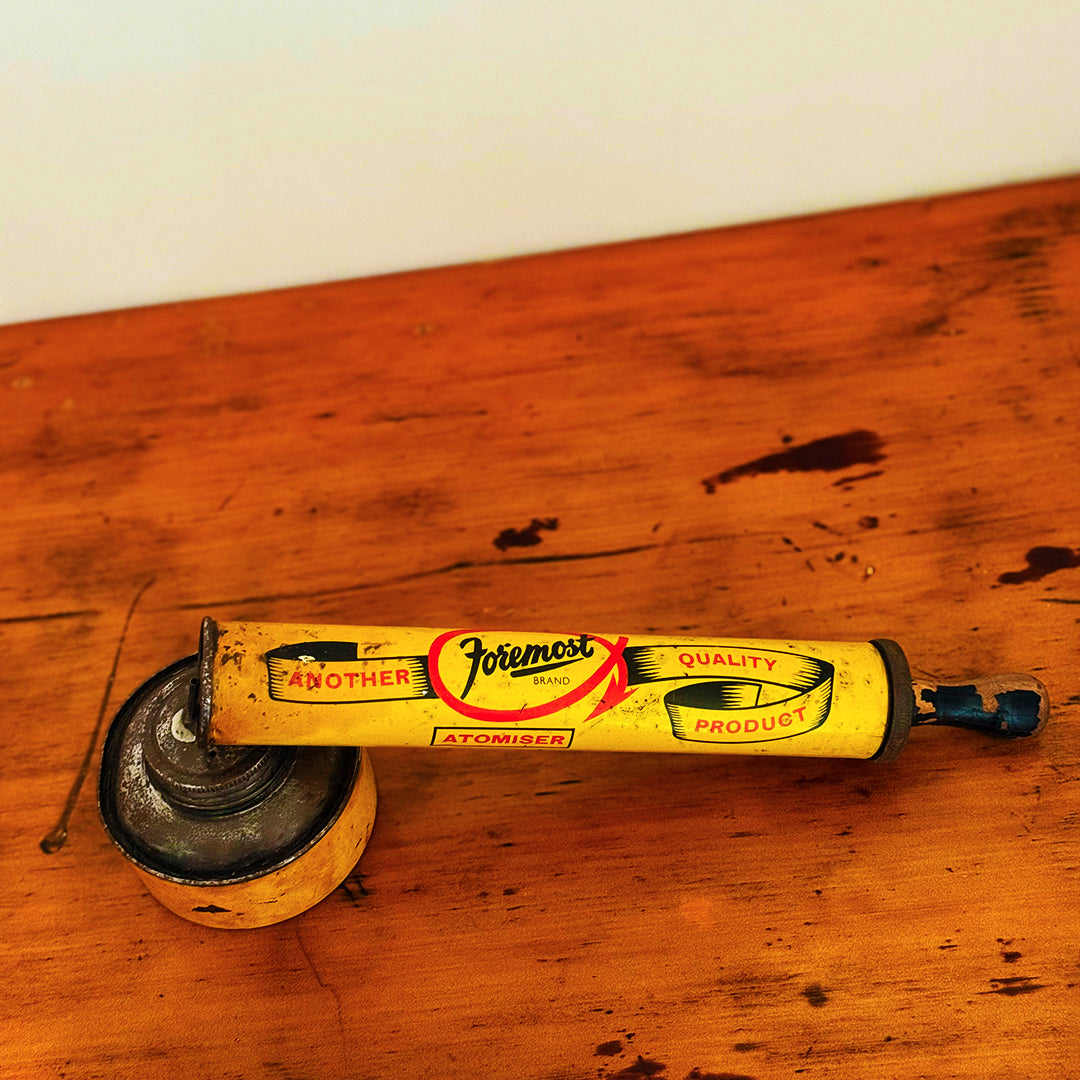 Vintage Insect Spray Hand Pump with red and worn surface, displaying classic mid-20th-century design, shown on a wooden surface.