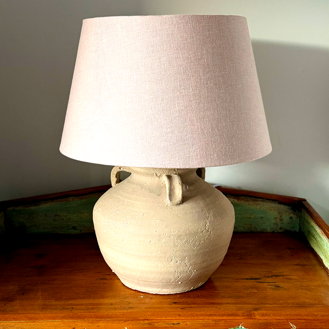 wabi - sabi Table lamp with a textured beige base and pinkish-brown lampshade on a wooden surface.