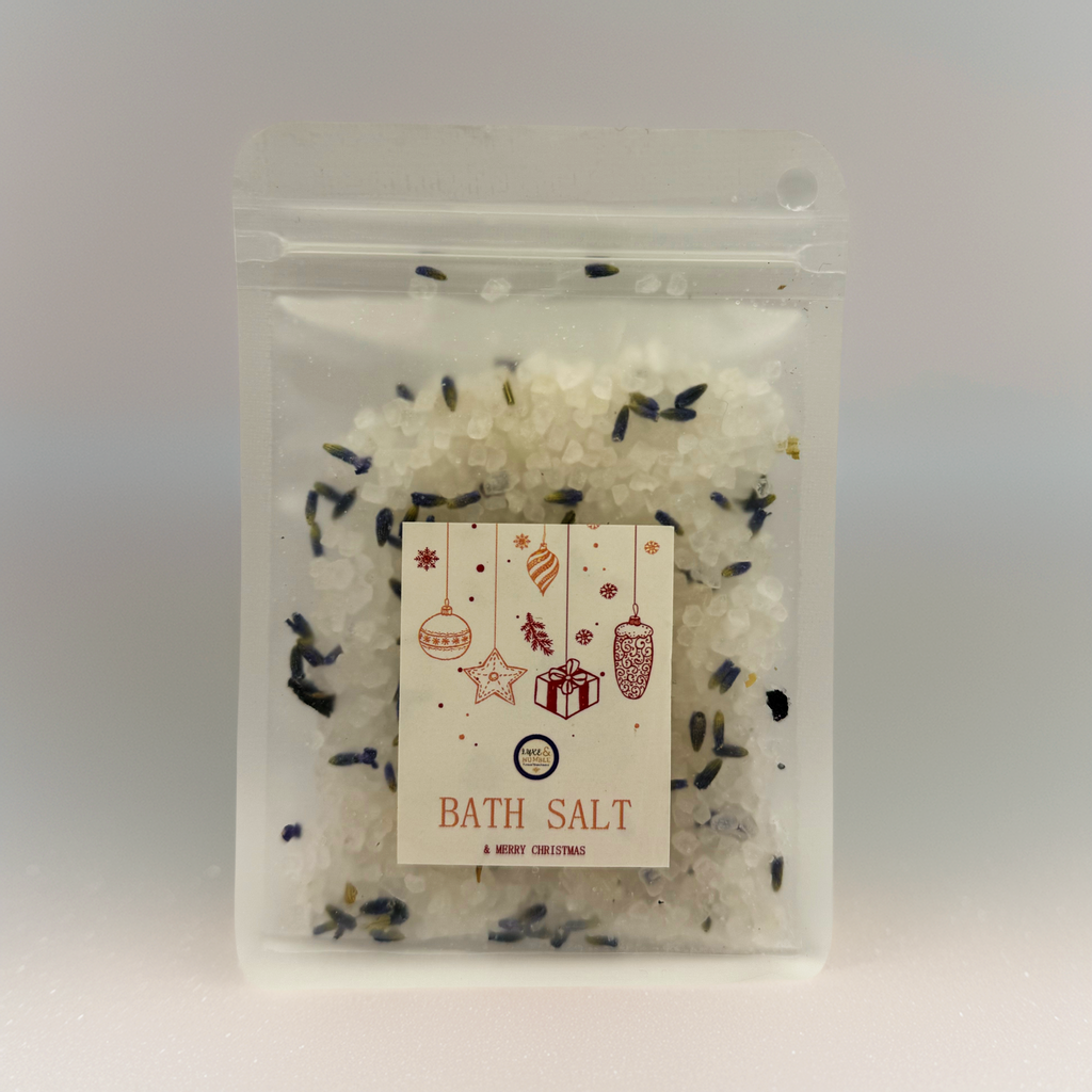 A Luxe & Humble Lavender Snow Christmas Bath Salt displayed in a clear stand-up pouch filled with white mineral salts and dried lavender buds. The front label features festive Christmas ornaments, stars and a gift illustration. The product is styled with warm golden bokeh lights and soft sparkle effects, creating a cosy holiday aesthetic ideal for Australian Christmas gifting and self-care.
