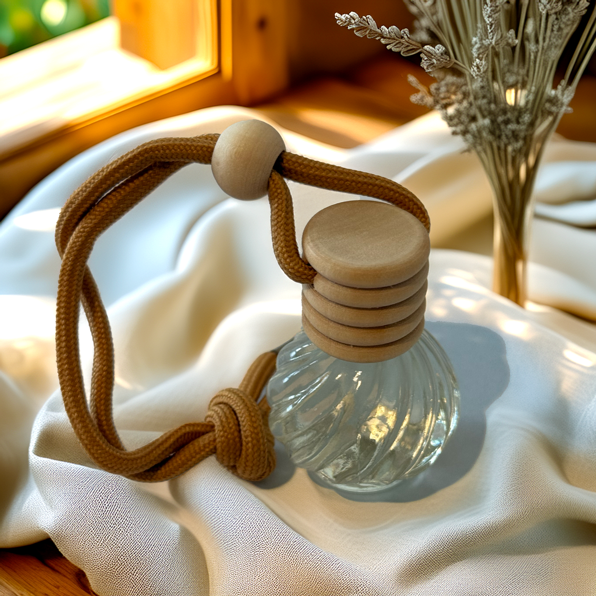 Bloom-shaped glass car diffuser with rustic rope top, filled with Montego Bay fragrance by Luxe & Humble, styled in soft rustic light.