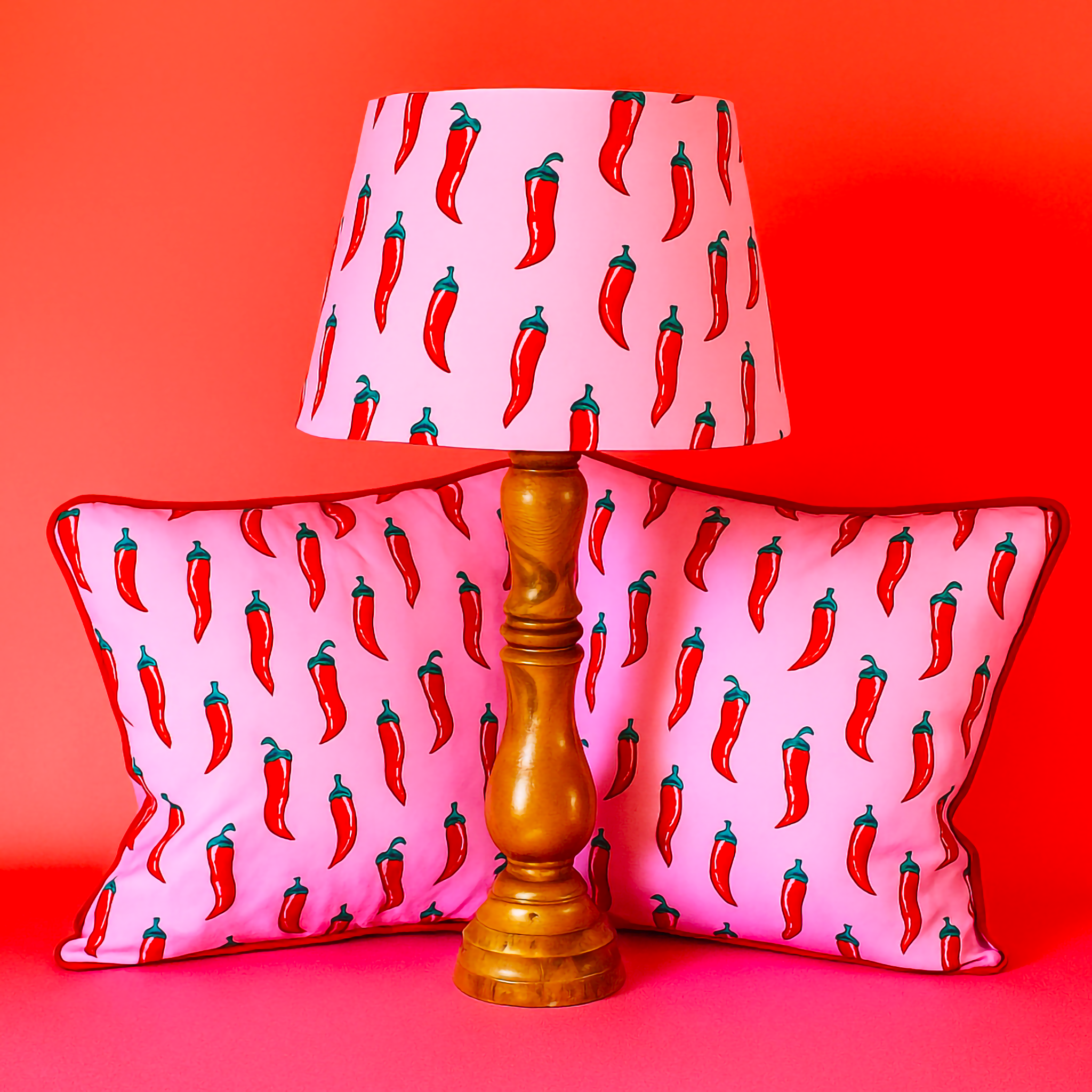 Lamp and cushions with red chili pepper pattern on a pink background