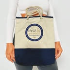 A model holding the Luxe & Humble navy and natural canvas tote bag with rope handles, highlighting scale and everyday usability. Clean, minimalist background with the signature Luxe & Humble logo clearly visible. Perfect for Australian lifestyle and fashion presentation.