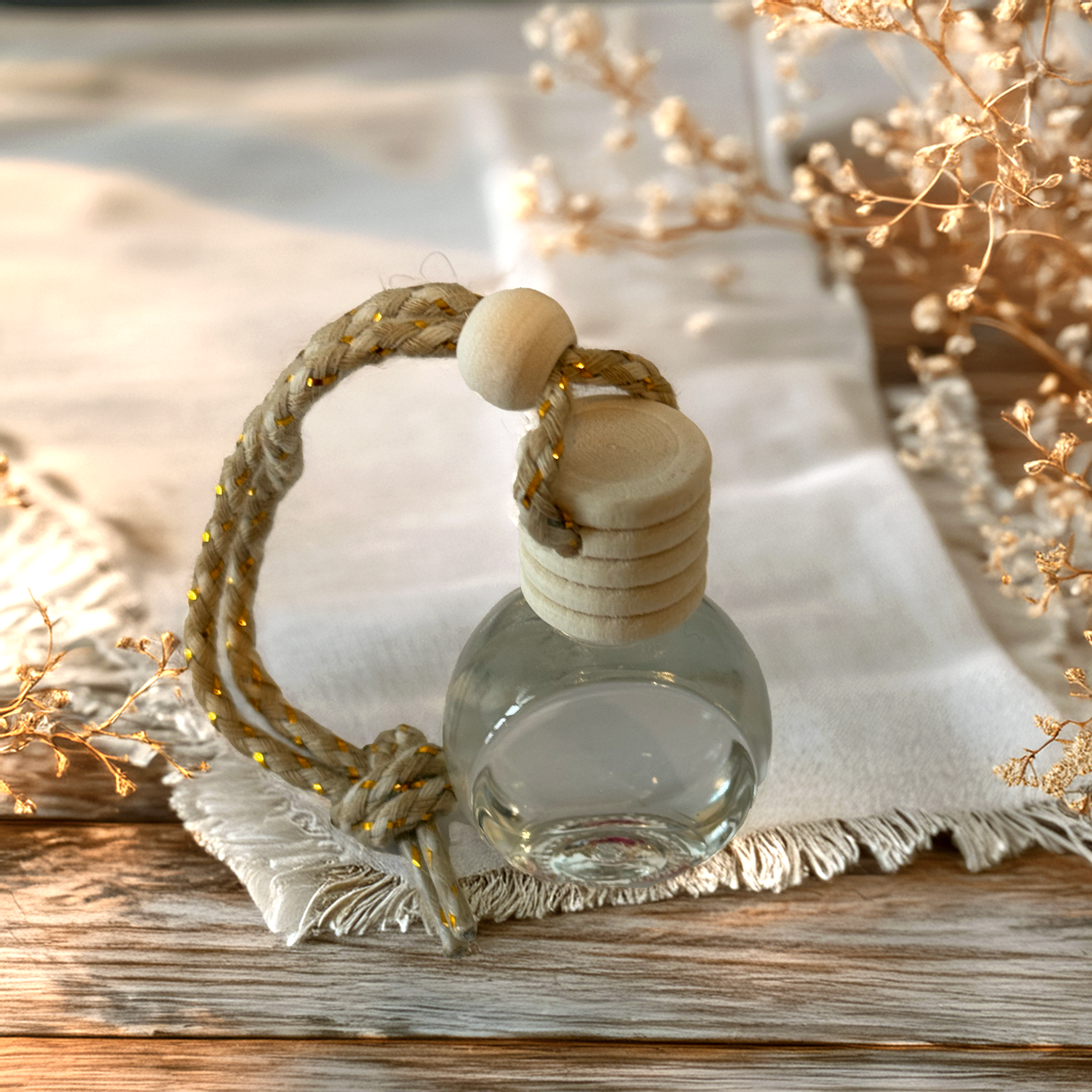 Orb-shaped glass car diffuser with rustic rope top, filled with Rose fragrance by Luxe & Humble, styled in soft natural light.
