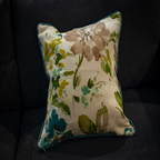 Luxe and Humble reversible cushion featuring a watercolour floral design in earthy neutrals, greens, and teal accents on natural linen, styled on a dark sofa for a fresh yet timeless interior look.