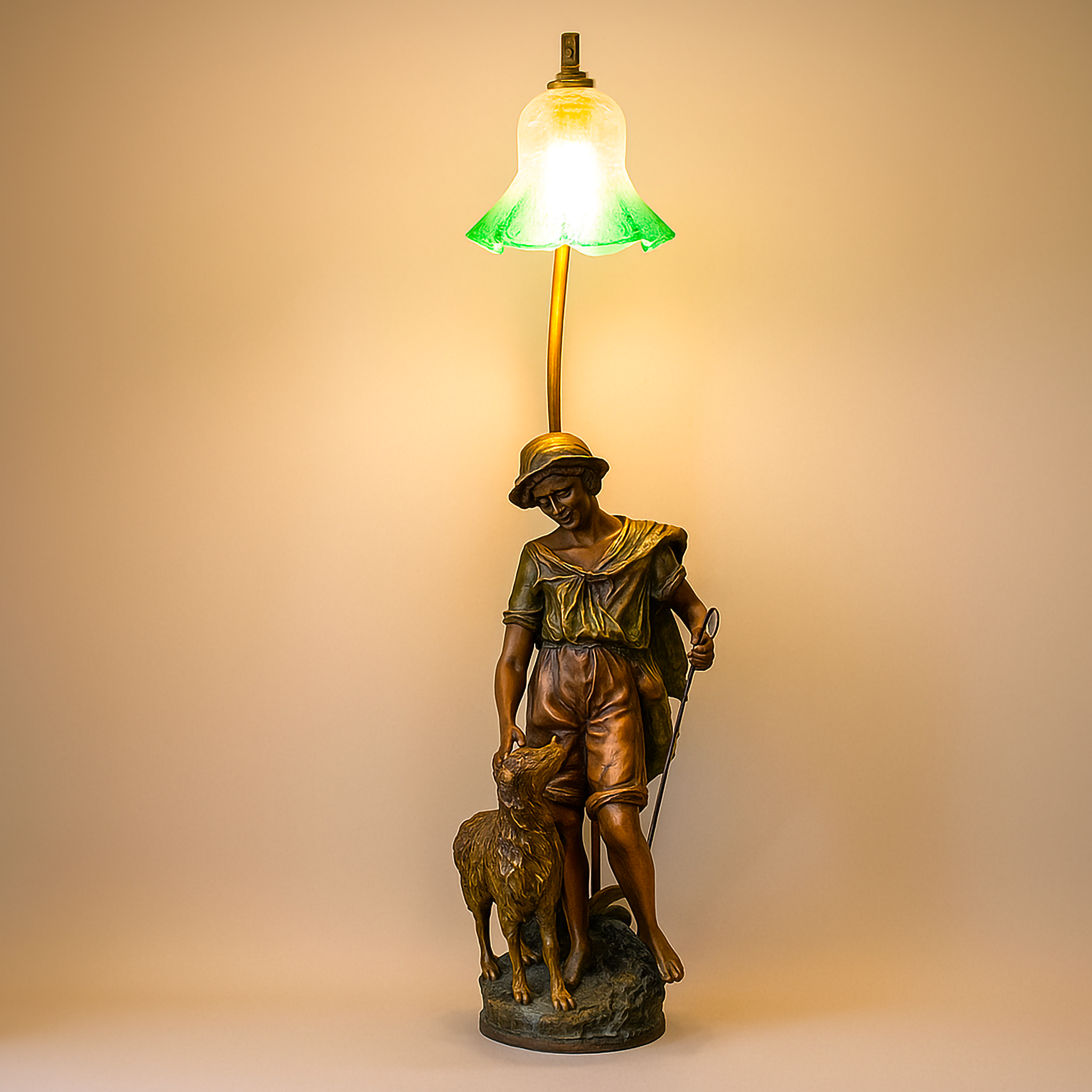 Elegant table lamp featuring a sculpted shepherd with his loyal dog in bronze tones, topped with a glowing green and white glass flower shade. Styled against a soft beige background, this Luxe and Humble piece combines heritage craftsmanship with warm ambient lighting for a timeless décor statement.