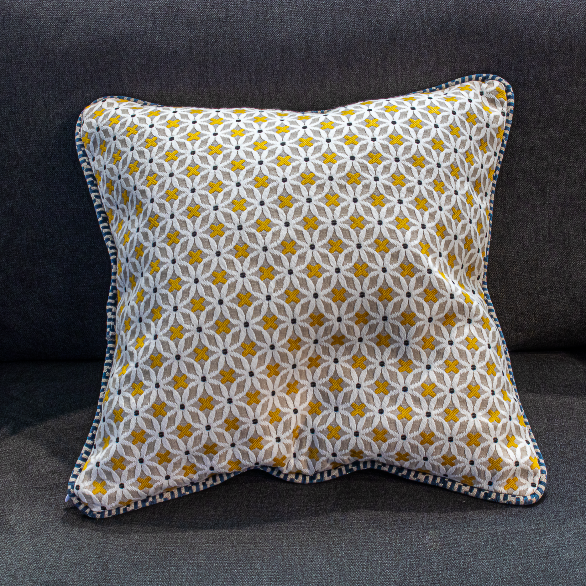 Luxe gold and white embroidered pillow cover featuring an intricate floral pattern with blue piping, adding a touch of elegance to your home décor.