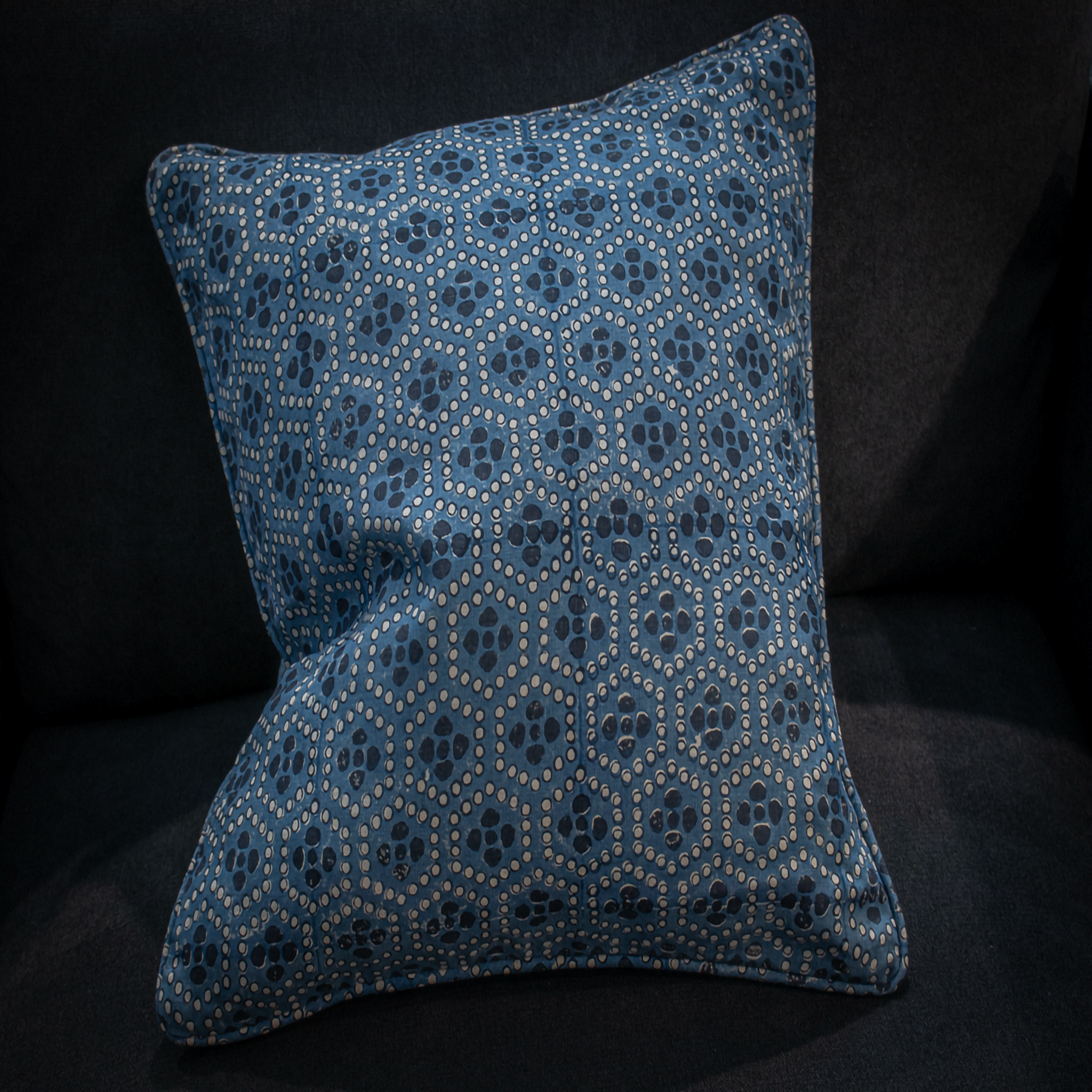 Close-up of the Mewari – Denim Ash Block Printed Scatter Cushion, showcasing the detailed denim blue and ash tones, displayed on a dark sofa.