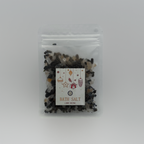 A Luxe & Humble Midnight Charcoal Christmas Bath Salt in a clear resealable pouch filled with dark charcoal mineral salts and light crystal accents. The festive label features hanging Christmas ornaments, stars and a gift illustration. Set against a clean studio background, this handcrafted Australian bath salt is ideal for Christmas gifting, stocking fillers and luxury self-care.