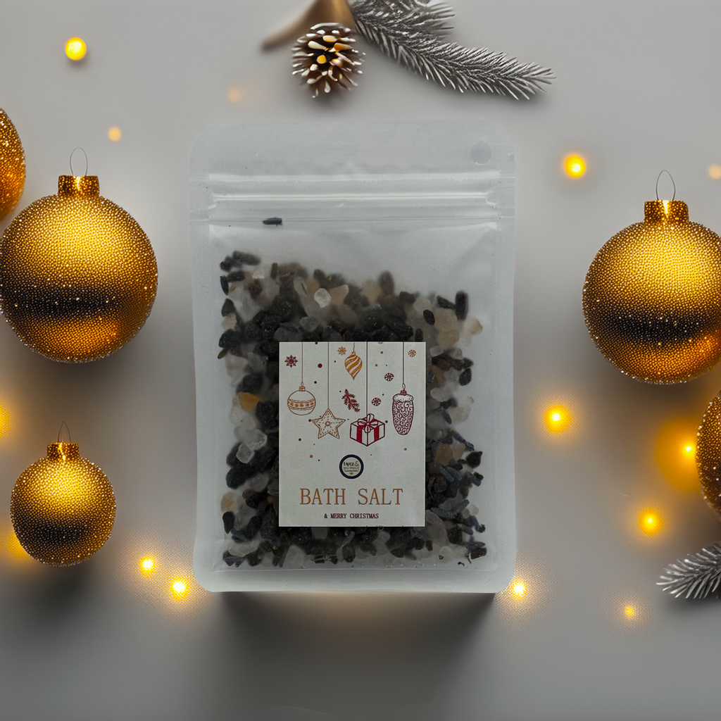 A Luxe & Humble Midnight Charcoal Christmas Bath Salt in a clear stand-up pouch filled with dark mineral bath salts. The festive Christmas label features ornaments, stars and a gift illustration. Minimal studio background highlights the handcrafted Australian holiday bath product, ideal for Christmas gifting and relaxation.
