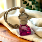 Pink heart-shaped glass car diffuser with rustic rope top, filled with Coconut Mango fragrance by Luxe & Humble, styled in natural light.