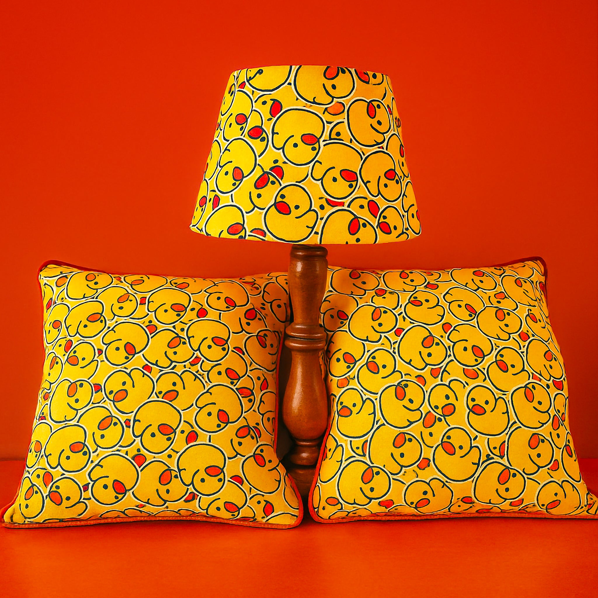 Duck print empire lampshade with matching 50 x 50 cm cushions styled on bright orange background

Playful yellow duck pattern lampshade and cushions with bold red-orange backdrop

Empire lampshade and bespoke cushions featuring cheeky duck print design for fun interiors

Vibrant duck print home decor set with lampshade and matching cushions on orange surface