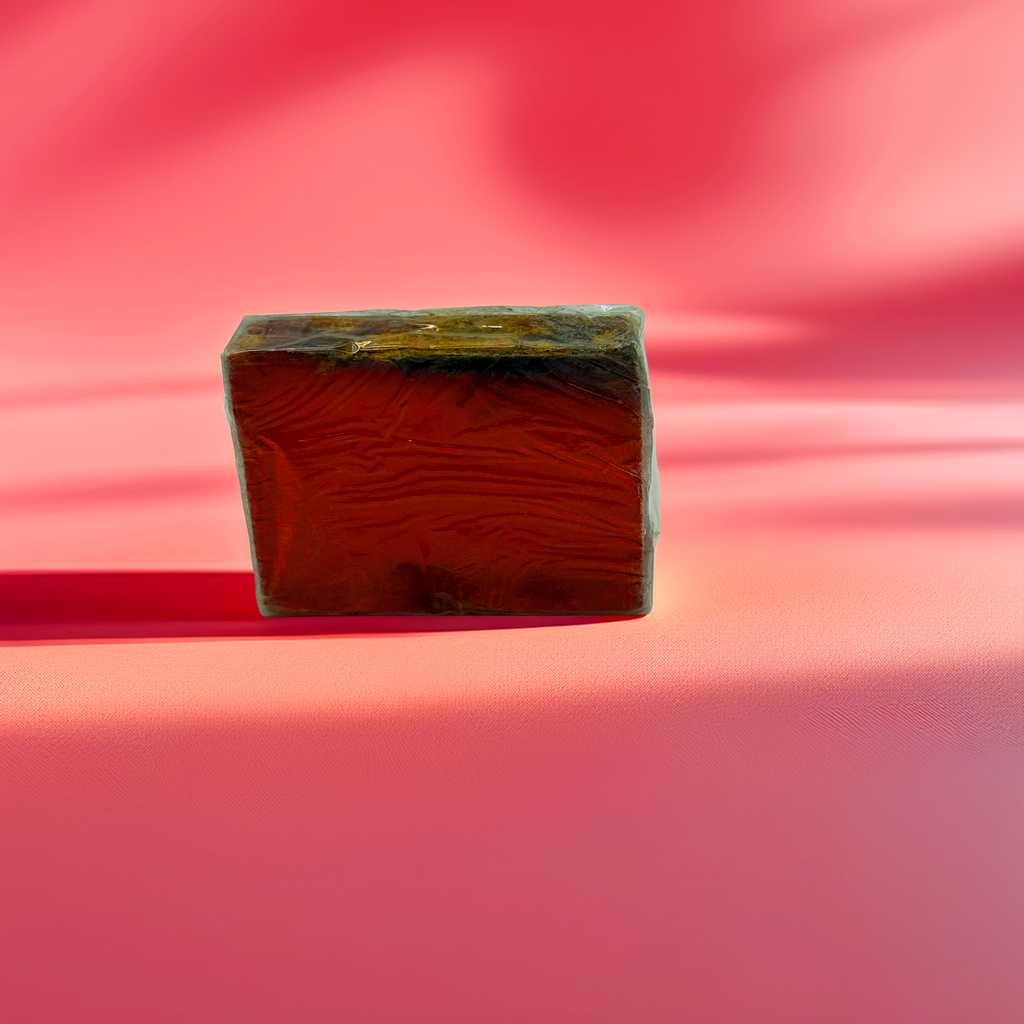 Handcrafted red-orange botanical soap bar with dried floral topping, displayed on a soft pink background with artistic shadows – Luxe & Humble Australia.