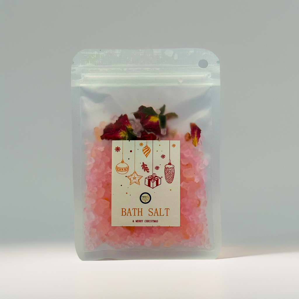 A Luxe & Humble Rose Blush Christmas Bath Salt presented in a clear stand-up pouch filled with pink mineral bath salts and dried rose petals. The front label features Christmas ornaments, stars and a festive gift illustration. Set against a clean, soft background, this product image highlights the handcrafted, Australian-made holiday bath salt—perfect for Christmas gifting, stocking fillers and luxury self-care.