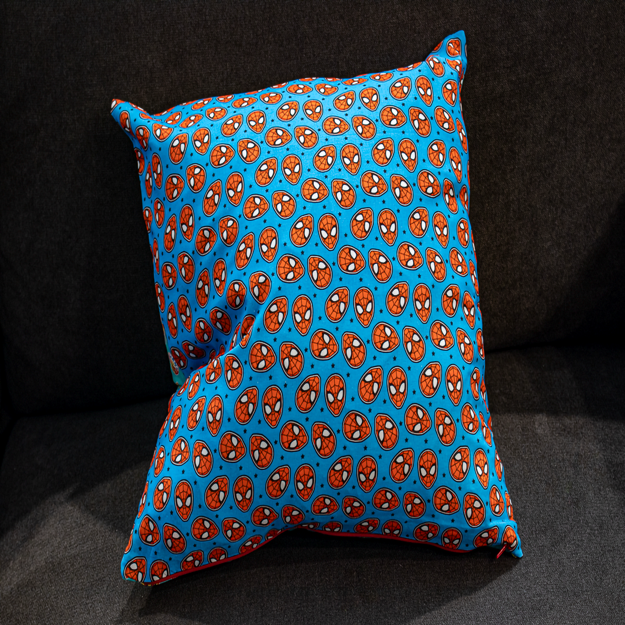 Reversible Spider-Man cushion featuring an all-over comic mask design on a bright blue background. This 50 x 50 cm pillow is perfect for Marvel fans, kids’ rooms, and superhero-themed decor. Luxe & Humble exclusive.