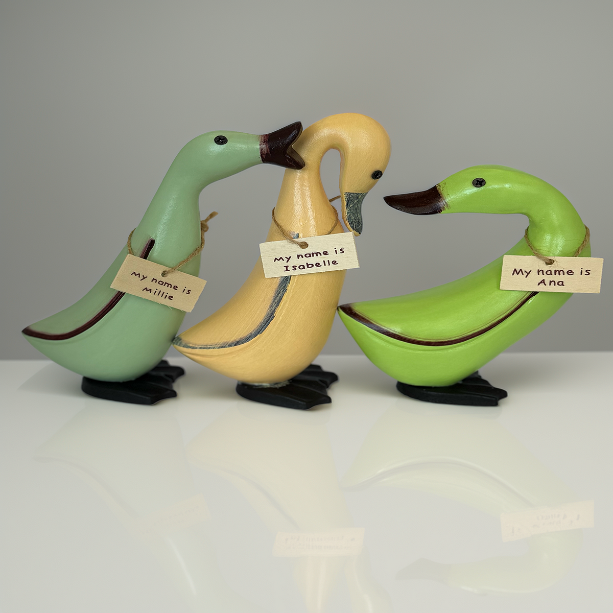 Hand-carved wooden duck trio in pastel green and yellow with name tags Millie, Isabelle and Ana. Artisan wooden duck ornaments for Australian home décor, coastal styling, nursery décor and farmhouse interiors. Luxe & Humble handcrafted décor Australia.