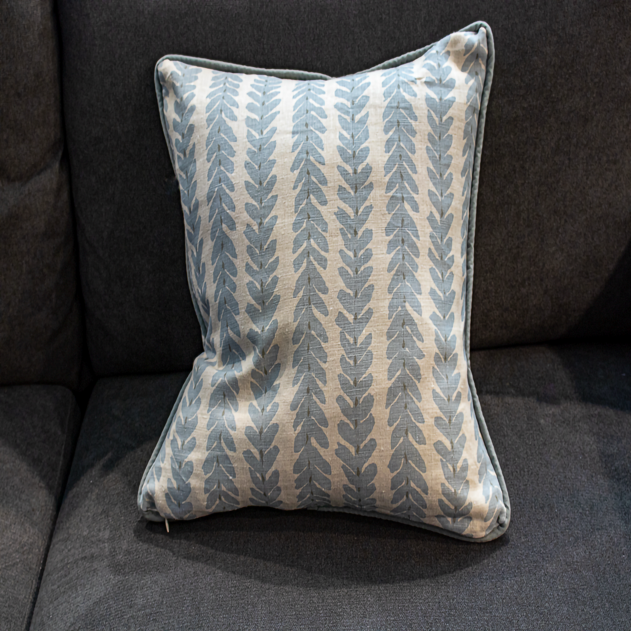 Decorative pillow with leaf pattern on a dark gray sofa - Fabric Woodyperry in blue by Schumacher from Luxe and Humble reversible