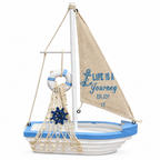 Decorative mini wooden sailing boat figurine featuring a blue and white hull, lifesaver wheel charm, and canvas sail on a plain white background.